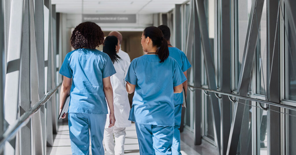 An image of several healthcare professionals walking across a skybridge at a medical facility
