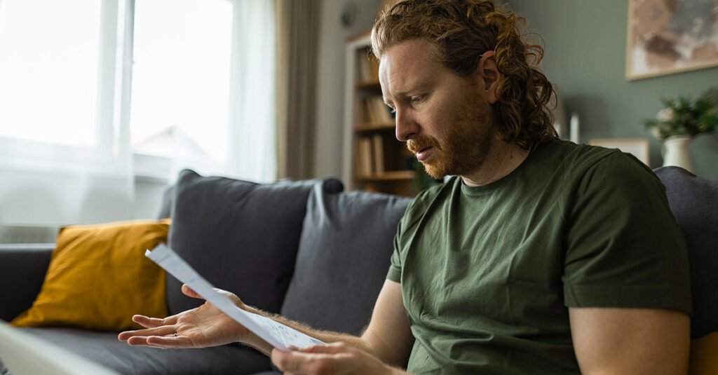 A confused Veteran sitting at home reviewing GI Bill materials