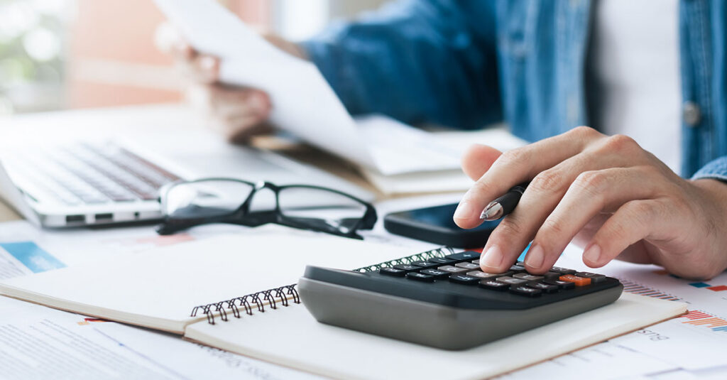 A person operating a calculator to calculate total benefit eligibility