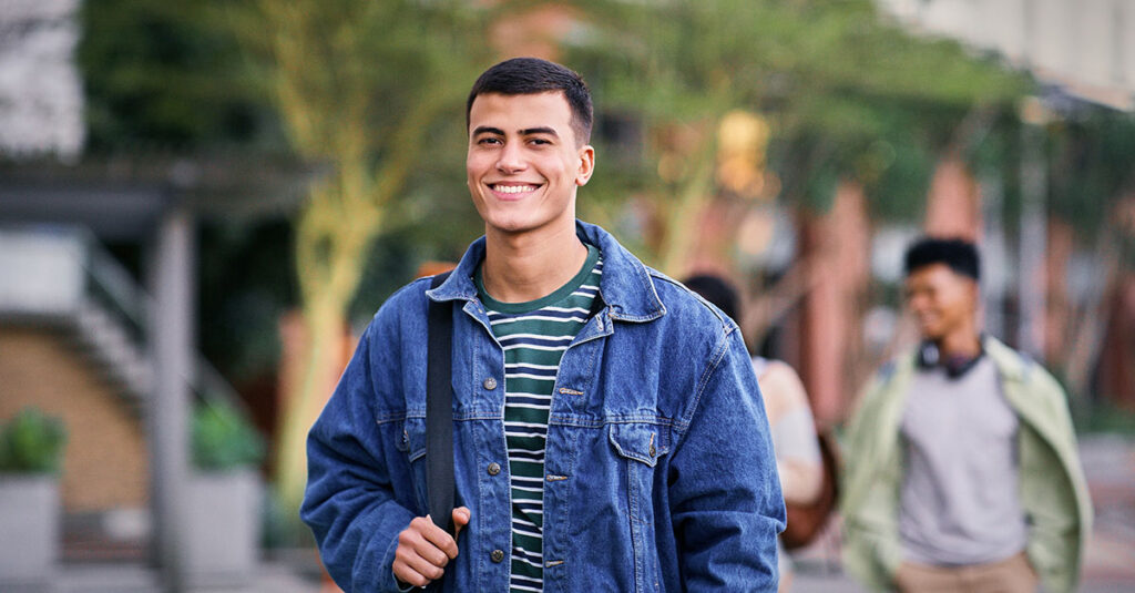 A student veteran smiling as he walks through a college campus